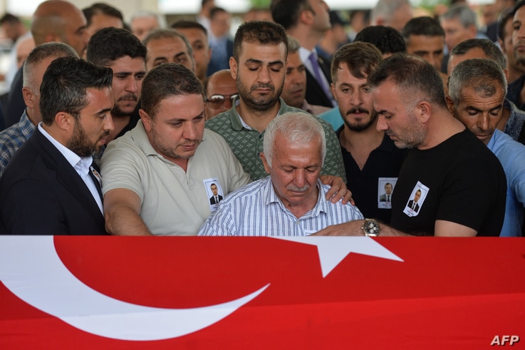 Relatives of Osman Kose, a 38-year-old Turkish diplomat killed in Iraq, mourne in front of the coffin covered with a Turkish…