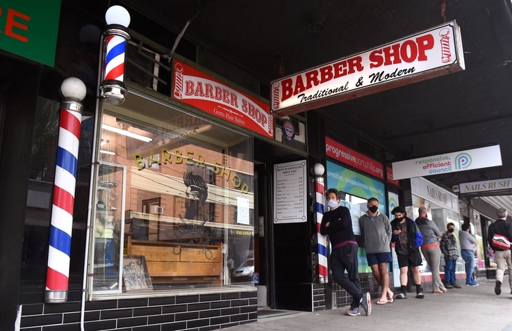 Men queue for a haircut outside a barber shop in Melbourne on October 19, 2020, as some of the city's three-month-old stay-at…