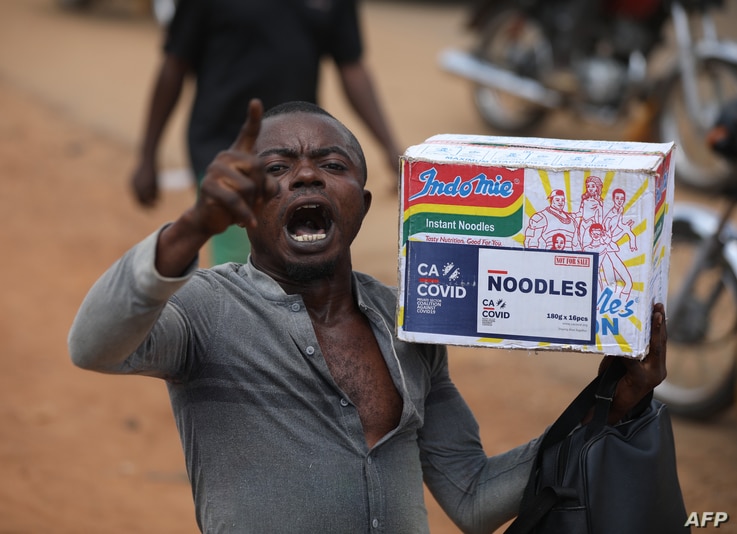 A man reacts while carrying a bag of noodles during a mass looting of a warehouse that have COVID-19 food palliatives that were…