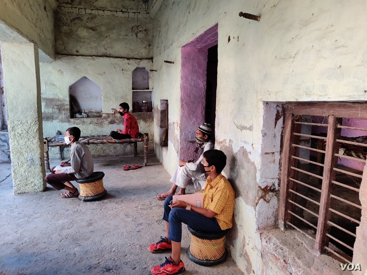 Some students sit in courtyards facing the street as a chemistry lesson is beamed into village homes. (Anjana Pasricha/VOA)