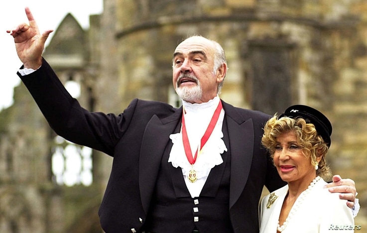 Sir Sean Connery, with wife Micheline (R), pose for photographers after he was formally knighted by the Britain's [Queen…