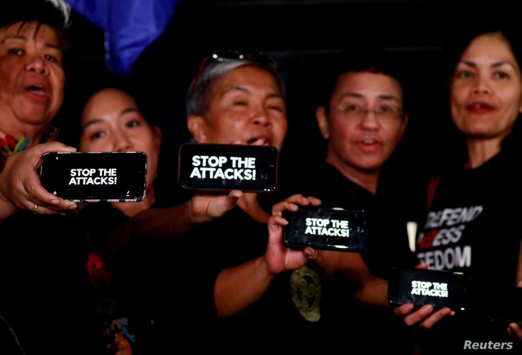Journalists, including Rappler CEO Maria Ressa, raise their smart phones with words 