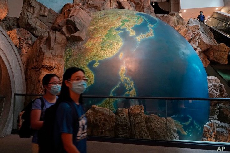 Visitors wearing masks to help protect against the coronavirus walk past an earth sculpture, at the Hong Kong Museum of History, in Hong Kong, Oct. 16, 2020. 