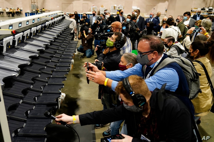 Media members photograph and record a sorting machine at Philadelphia's mail-in ballot sorting and counting center in…