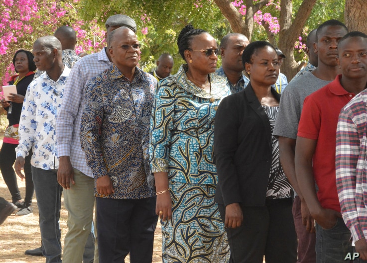 The ruling party CCM presidential candidate Dr. John Magufuli, third left, stands in line to cast his vote at Chamwino in Dodoma, Oct. 28, 2020.
