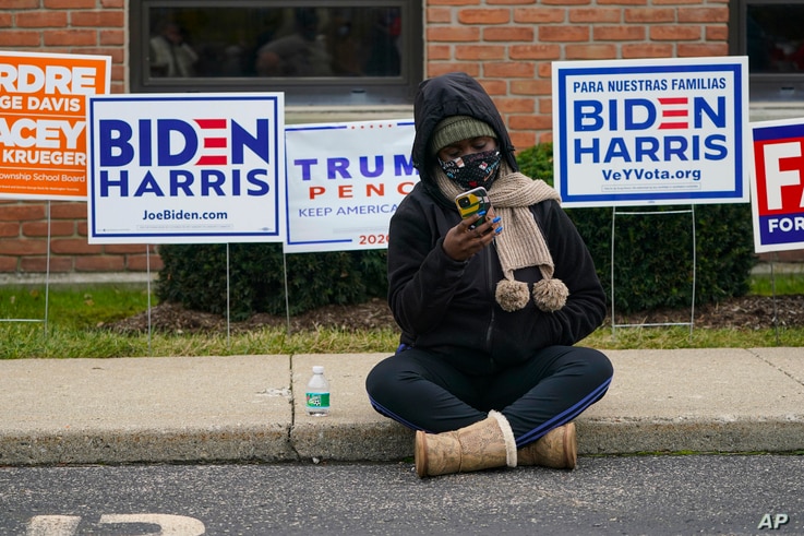 A voter sits on the sidewalk as voters wait in long lines to cast their ballots during early voting at St. Luke's United…