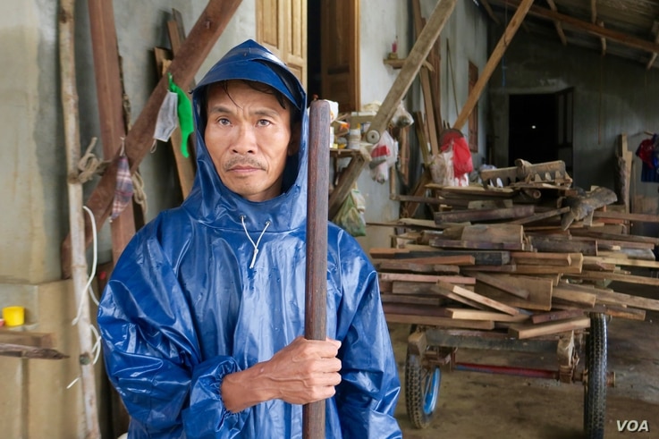 A local man wearing a raincoat stands near a home that was recently flooded in Quang Tri.