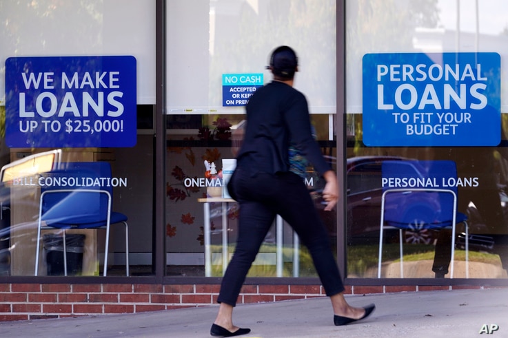 FILE - A woman walks past a personal finance loan office in Franklin, Tennesee, Oct. 1, 2020.