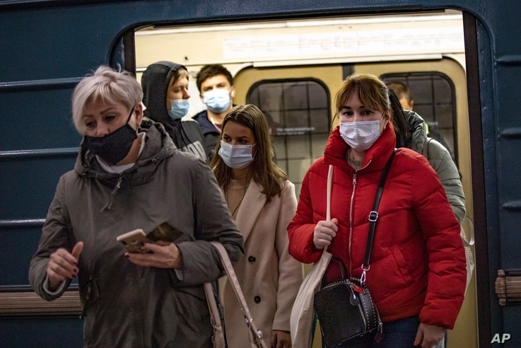 People wearing face masks to protect against the coronavirus exit a subway car in Moscow, Russia, Oct. 19, 2020.