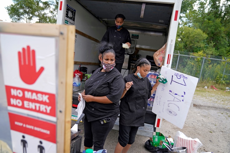 Tequila Butler, left, sets up her taco stand out of the back of a U-Haul truck with her daughters, Alliyah, 15, rear, and…