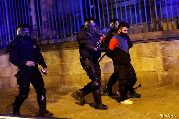 A demonstrator is detained by police officers during a protest against police raids and the arrest of Catalan separatists, in Barcelona, Spain, Oct. 28, 2020. 