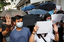 Supporters raise white paper to avoid slogans banned under the national security law as they support arrested anti-law protester outside Eastern court in Hong Kong