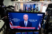 President-elect Joe Biden speaks about coronavirus as he appears on a television in the Brady Press Briefing Room of the White…
