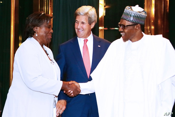 United States Secretary of State John Kerry (C) reacts as Nigerian President Muhammadu Buhari (R) shakes hands with Assistant…