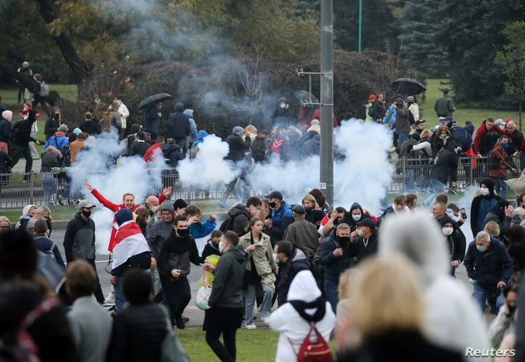 Demonstrators react as a stun grenade explodes during an opposition rally to reject the presidential election results in Minsk, Belarus, Oct. 11, 2020.