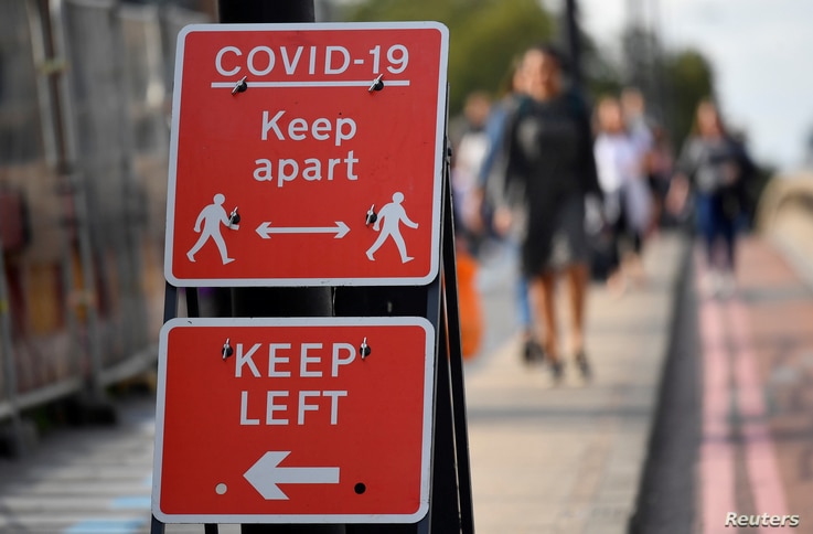 FILE PHOTO: Pedestrians walk near public health signs in London, Britain, September 11, 2020. REUTERS/Toby Melville/File Photo
