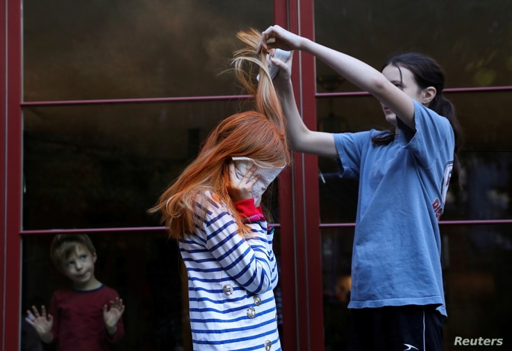 Jane Hassebroek helps her sister Lydia to dye her hair for a Chuckie costume for Halloween at their home, as the coronavirus…