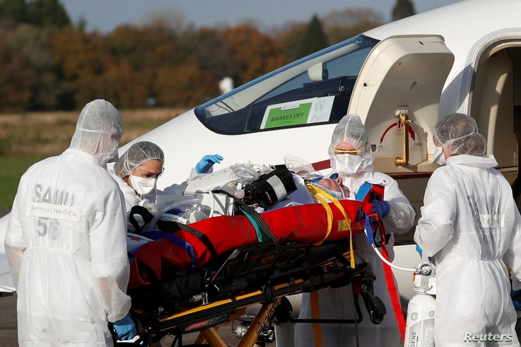 Medical staff members move a patient from a plane during a transfer operation of people suffering from the coronavirus disease …