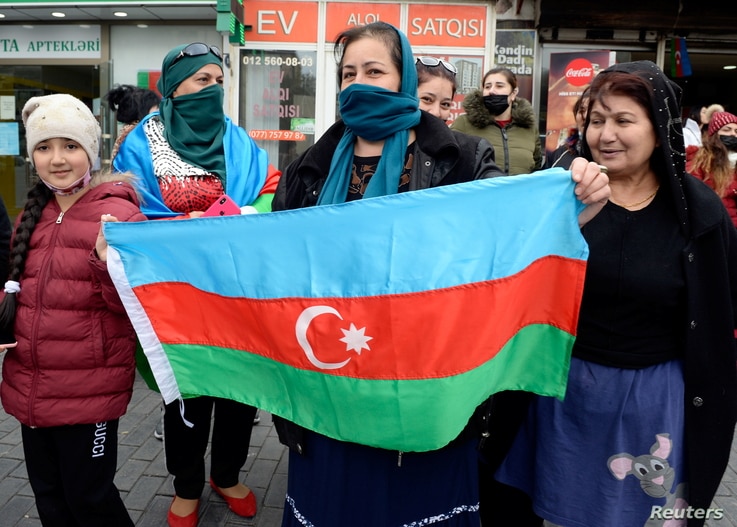People hold the national flag as they celebrate on the streets after Azerbaijan's President Ilham Aliyev said the country's…