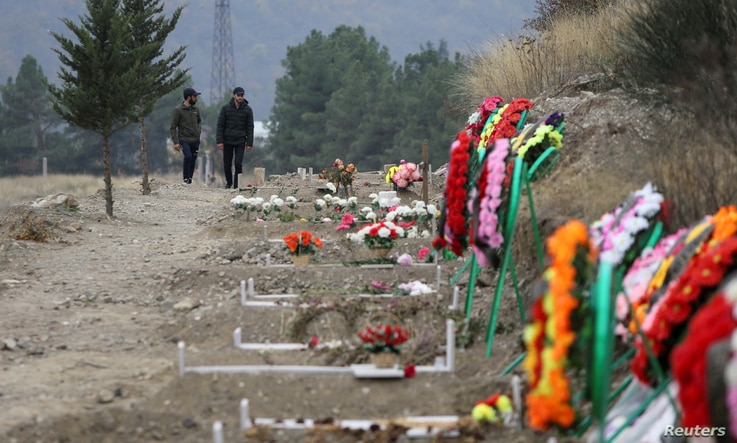 FILE PHOTO: Men walk along graves of soldiers and civilians who were killed during a military conflict over the breakaway…