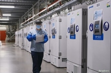 FILE - A worker passes a line of freezers holding coronavirus disease (COVID-19) vaccine candidate BNT162b2 at a Pfizer facility in Puurs, Belgium in an undated photograph. 