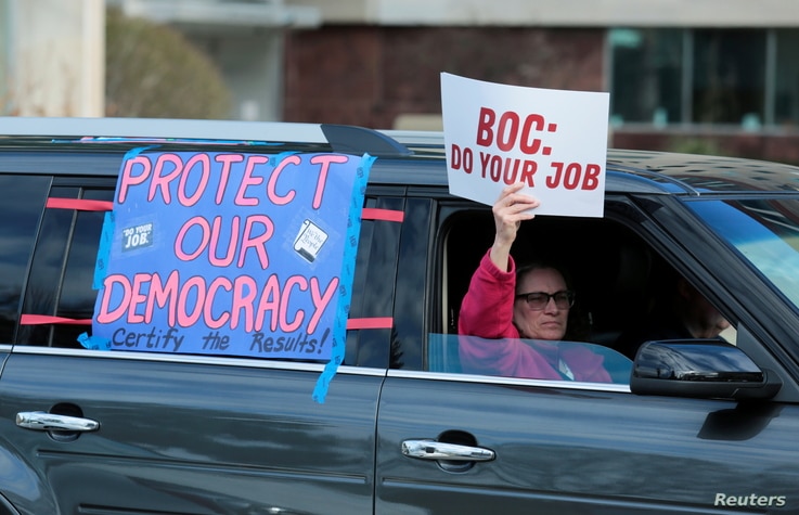 Demonstrators in a car caravan demand the Board of State Canvassers to  certify the results of the election in Lansing,…