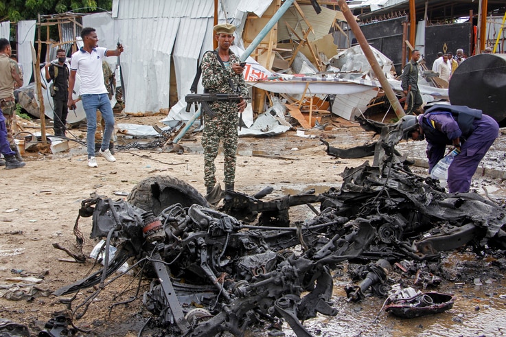 Security forces stand next to wreckage at the scene of a suicide car bomb attack in the capital Mogadishu, Somalia Monday, July…