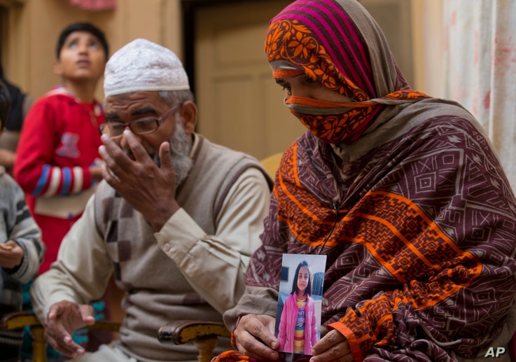 Nusrat holds a photo of her daughter, Zainab Ansari, who was raped and killed, as her husband, Mohammed Amin in Kasur, sits beside her in Kasur, Pakistan, Jan. 18, 2018.