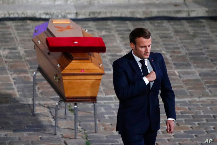 French President Emmanuel Macron leaves after paying his respects by the coffin of slain teacher Samuel Paty in the courtyard…