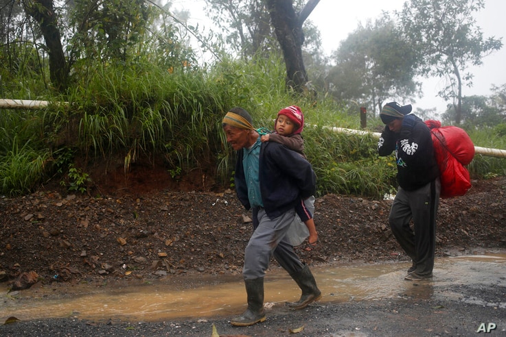 People walk around a road blocked by a landslide in San Cristobal Verapaz, Saturday, Nov. 7, 2020, in the aftermath of…