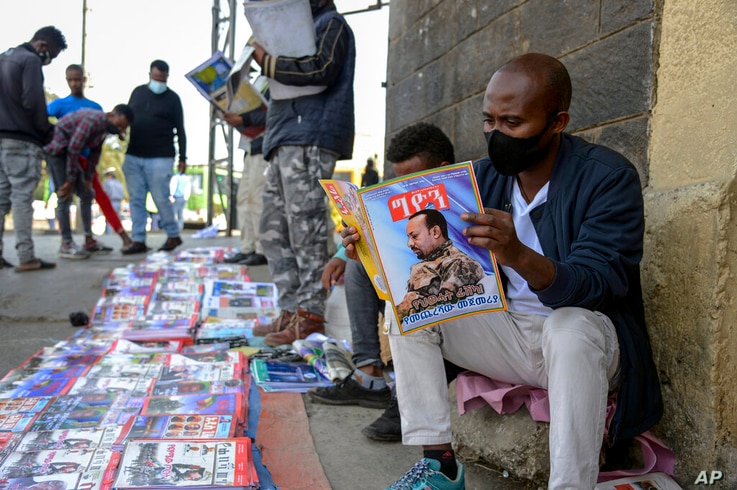 Ethiopians read newspapers and magazines reporting on the current military confrontation in the country, one of which shows a…