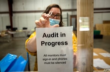 A Chatham County election official posts a sign in the public viewing area before the start of a ballot audit, Nov. 13.