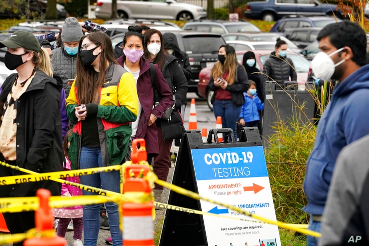 FILE - In this Nov. 18, 2020, file photo, people line up to be tested for the coronavirus at a free testing site in Seattle…