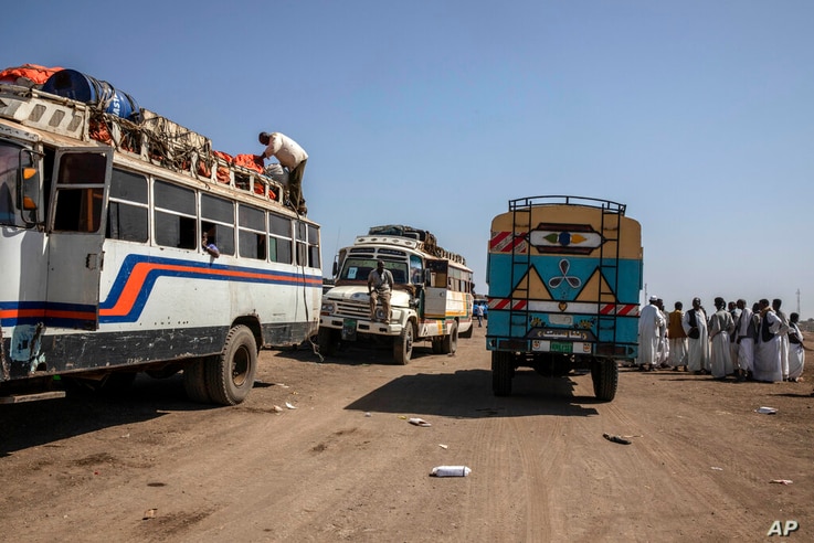 Sudanese men, right, help Tigray refugees who fled the conflict in the Ethiopia's Tigray, ride buses enroute to Qadarif to seek…