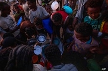 Tigray men who fled the conflict in Ethiopia's Tigray region, receive cooked rice from charity organization Muslim Aid, at Umm…