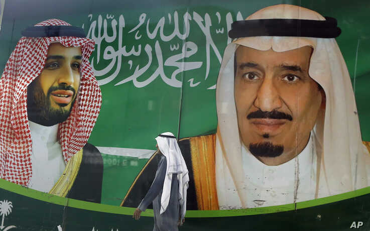 A man walks past a banner showing Saudi King Salman, right, and his Crown Prince Mohammed bin Salman, outside a mall in Jiddah, Saudi Arabia, March 7, 2020.