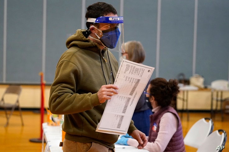Julian St. Laurent wear a face shield and two face masks to help prevent the spread of the coronavirus as he walks to a voting…