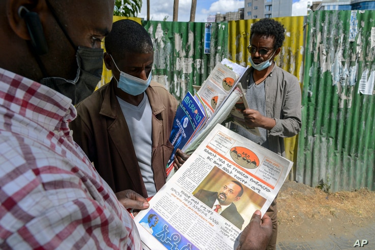 Ethiopians read newspapers and magazines reporting on the current military confrontation in the country, one of which shows a…