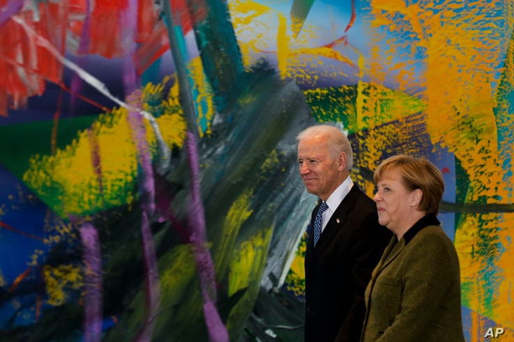 German Chancellor Angela Merkel, right, walks with United States' Vice President Joe Biden for a meeting at the chancellery in…