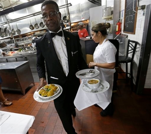 Waiter Austin Murray brings plated dishes from the kitchen to the dining room at Antoine's Restaurant in New Orleans, Sept. 11, 2015. 