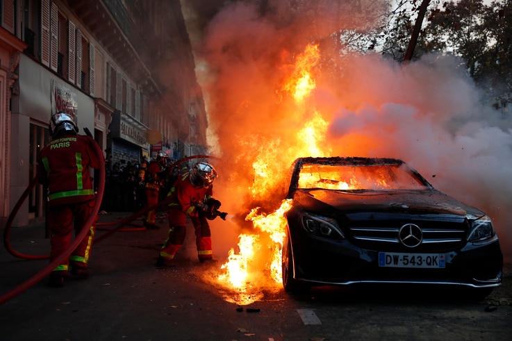Fire-fighters pull off a fire on a burning car during a demonstration against a security law that would restrict sharing images…