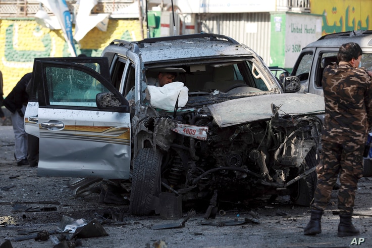 Security forces inspect a damaged vehicle at the site of a bomb explosion in Kabul, Afghanistan, Nov 16, 2020.