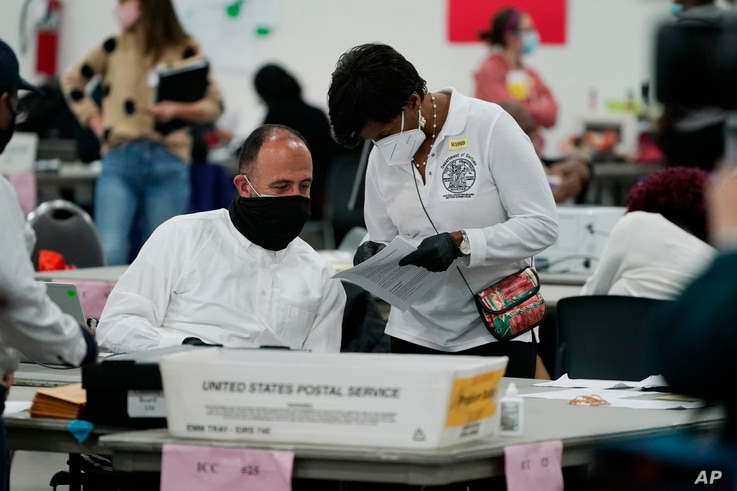 A worker checks with an election supervisor at the central counting board, in Detroit, Michigan, Nov. 4, 2020.