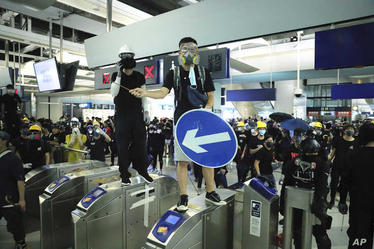 Demonstrators stand on turnstiles during a protest at the Yuen Long MTR station in Hong Kong, Aug. 21, 2019.