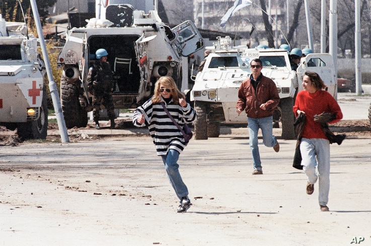 FILE - Civilians run along Sarajevo’s notorious “Sniper Alley,” as French U.N. peacekeepers look on, April 5, 1995. 