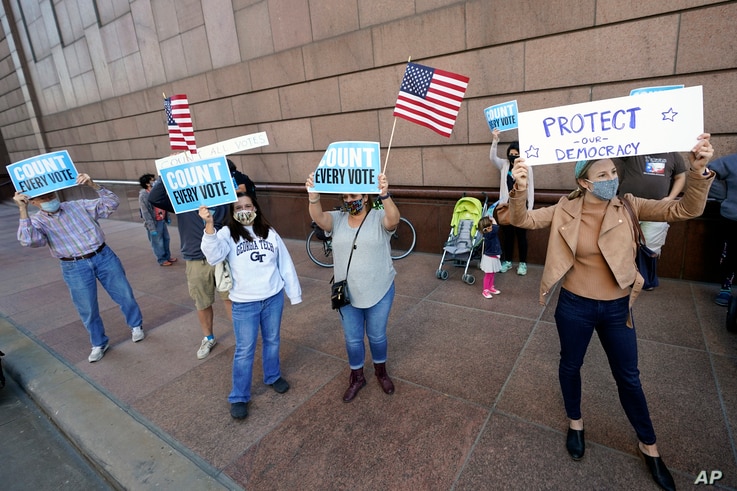 Demonstrators stand across the street from the federal courthouse in Houston, Texas, Nov. 2, 2020, before a hearing in federal court involving drive-thru ballots cast in Harris County.