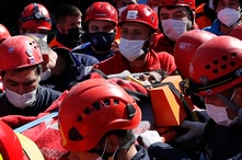Medics and rescue personnel carry into an ambulance an injured person from the debris of a collapsed building in Izmir, Turkey,…