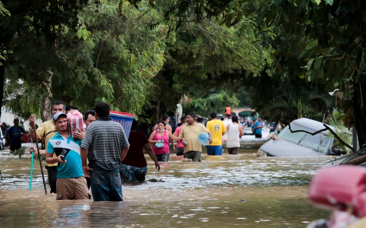 Residents walk past inundated vehicles in the flooded streets of Planeta, Honduras, Friday, Nov. 6, 2020, in the aftermath of…