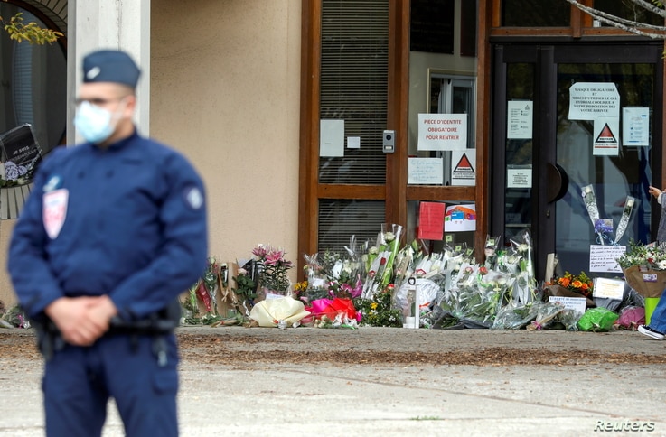 Flowers are stacked outside the school where slain history teacher Samuel Paty was working, in Conflans-Sainte-Honorine, northwest of Paris, France, Oct. 17, 2020.