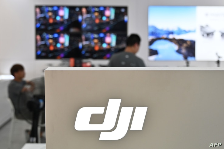 People are seen in a DJI store in Shanghai on May 22, 2019. (Photo by Hector RETAMAL / AFP)